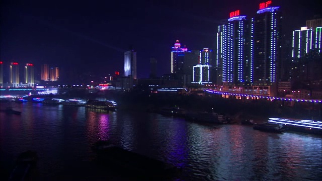 夜晚，耀眼的霓虹灯照亮了中国重庆的滨水摩天大楼。视频素材