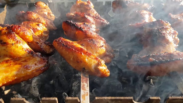 烤鸡的特写镜头。烹饪烤鸡翅。在烤架上烧烤食物。烤夏天做饭。放松的概念，食物，家庭和放松视频素材