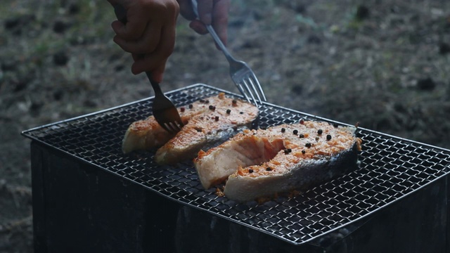 烧烤三文鱼用叉子烧烤。烤鲑鱼排视频素材