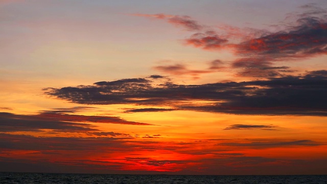 夕阳黄橙色的天空和暗红色的云在海上移动视频素材