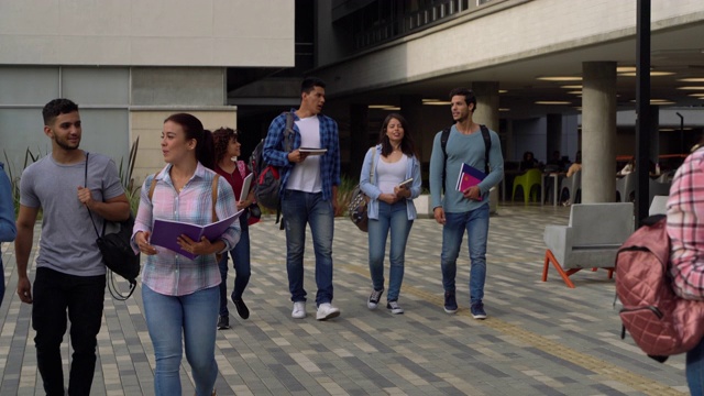 经过一天漫长的课堂后，大学生们走出校园，面带微笑地散步视频素材