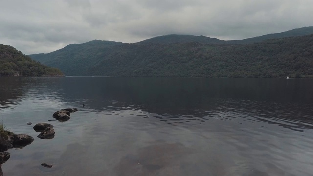 飞过苏格兰的一个湖泊，背景是山脉和植被。神奇的景观。空中无人机视图视频素材