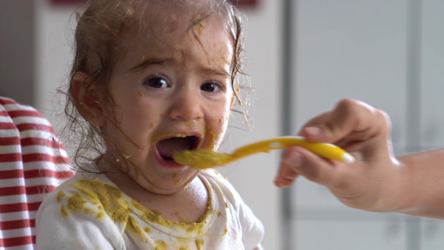 女婴坐在喂食椅上吃婴儿食品的超高清视频视频素材