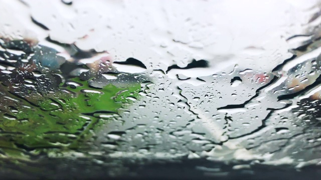 雨点是汽车挡风玻璃上的水滴，伴随着模糊的交通运动视频素材