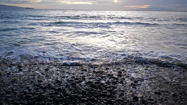 日落时海浪拍打着岩石海滩视频素材