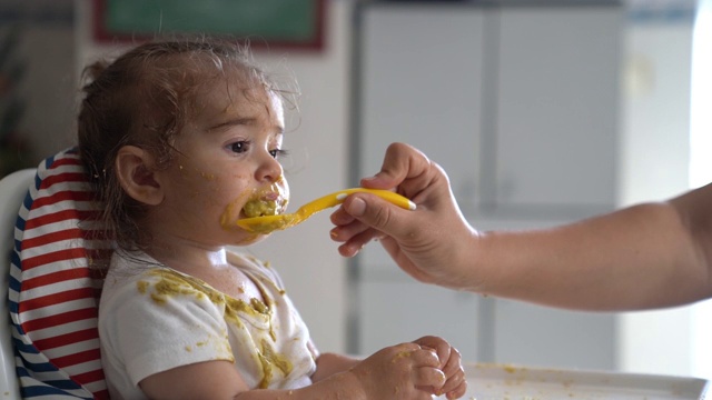 慢动作高清视频的婴儿女孩坐在喂食椅和吃婴儿食品视频素材