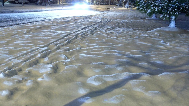 积雪覆盖的乡村小区道路上，冬夜自然车灯步道视频素材