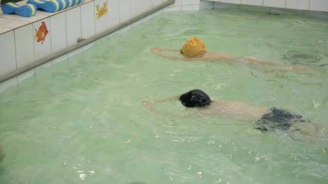 孩子们在游泳池里学习游泳。在学校的游泳池游泳。孩子们学游泳，孩子们比赛视频素材