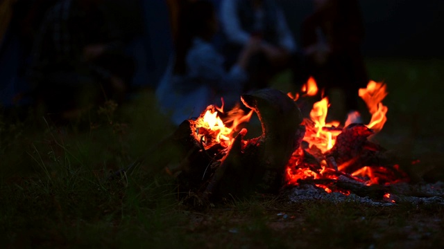 篝火在晚上与露营的人在草地上野炊的背景。在黑暗的篝火。橙色和黄色的火能源燃料。4K视频片段视频素材