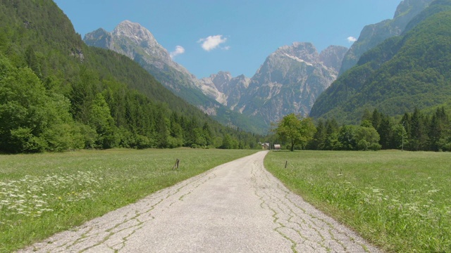 无人机:破碎的道路穿过令人惊叹的山脉下的草地。视频素材