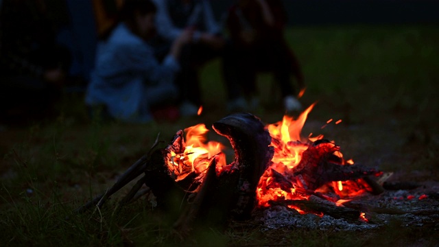 篝火在晚上与露营的人在草地上野炊的背景。在黑暗的篝火。橙色和黄色的火能源燃料。4K视频片段视频素材