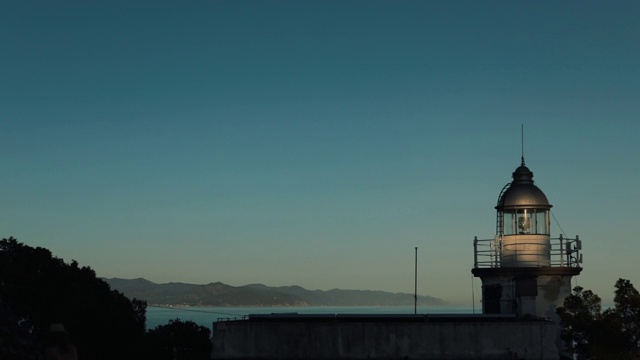 灯塔在海岸边，在海边，以山为背景。视频素材