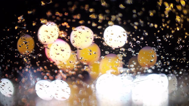 雨点模糊地落在一辆车上，以散焦圈红绿灯为背景，动作缓慢视频素材