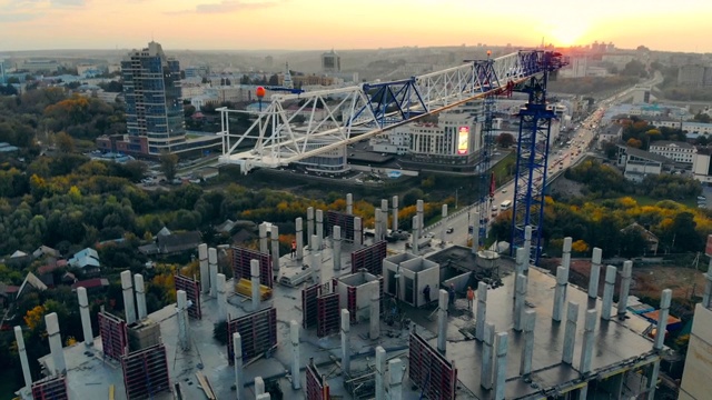 夕阳下的建筑工地。城市建筑工地，起重机和日落的城市景观视频素材