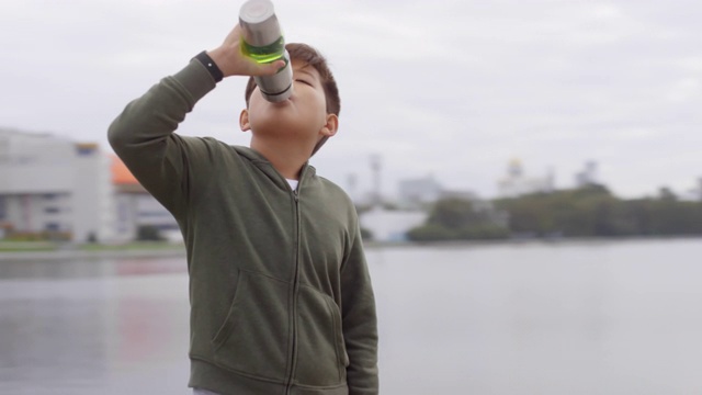 亚洲男孩在户外跑步后喝水视频素材