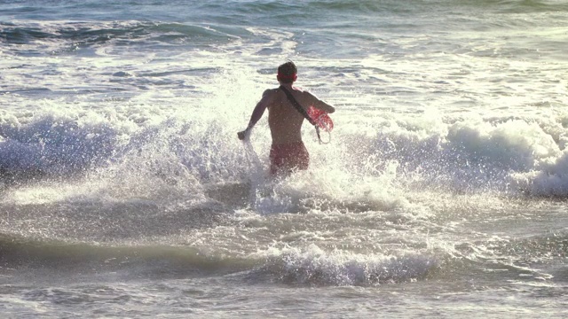 男救生员沿着海滩跑步视频素材