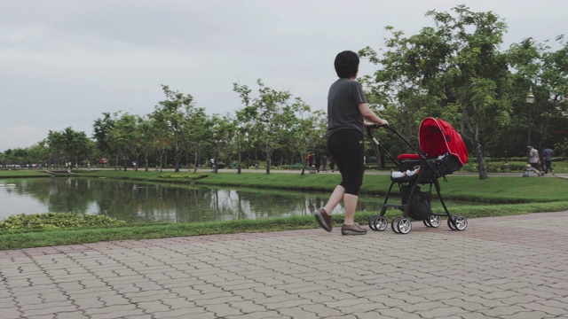 婴儿;母亲走着，推着婴儿车里的男孩视频素材