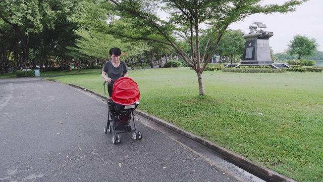 婴儿;母亲走着，推着婴儿车里的男孩视频素材