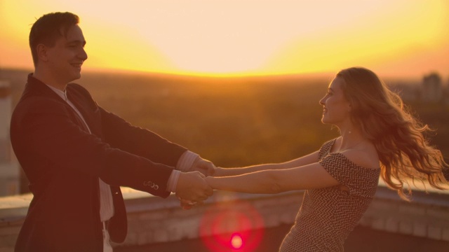 一个相爱的男人和一个相爱的女人在夕阳下站在屋顶上跳舞看着对方视频素材