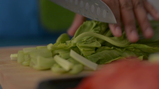 近距离拍摄的女人的手切白菜在木砧板上的健康食物在桌子上。视频素材