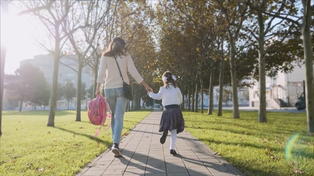 一个穿着校服的女人和一个小女孩在公园里跑步视频素材