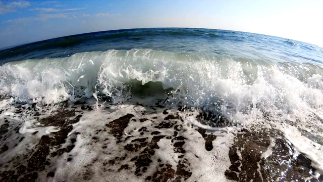 在一个阳光明媚的夏日，海浪拍打着海岸，慢镜头视频素材