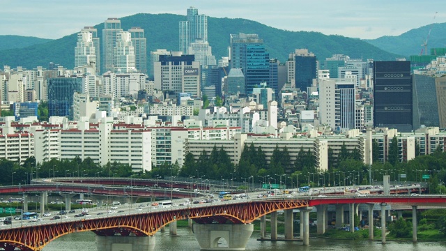 以首尔城市景观为背景，拍摄横跨汉江的大桥上的交通情况视频素材