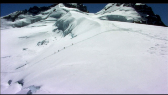 登山者艰难地爬上积雪的山坡。视频素材