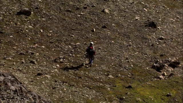 浓雾笼罩着一个郁郁葱葱的山坡，登山者在那里徒步旅行。视频素材