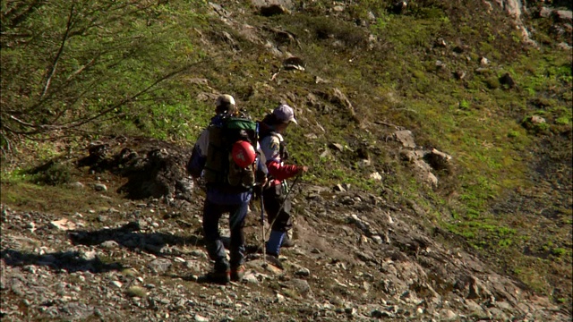 两个徒步旅行者走向一个被雾覆盖的山坡。视频素材