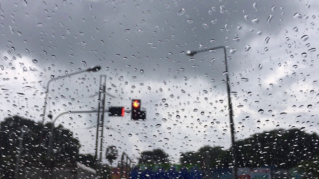 红灯路口下起了雨，挡风玻璃上有雨滴。视频素材