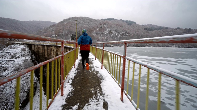 冬天，在结冰的湖边的一座雪桥上跑步视频素材