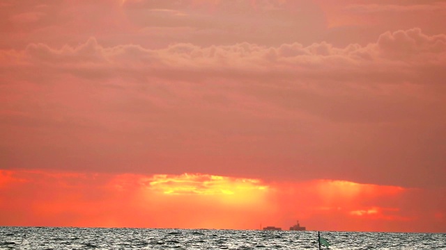 模糊的夕阳，橙色的天空和红色的云移动，海浪在海上视频素材