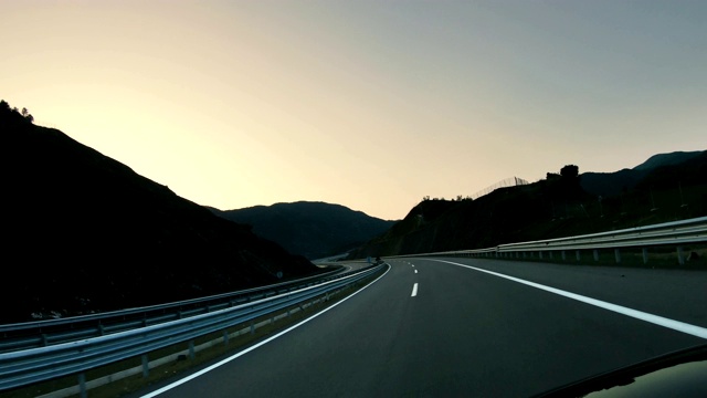 高速公路的道路在日出或日落时对着山脉和天空行驶视频素材