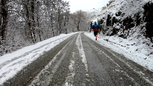 活跃的健康男子在寒冷的水在冬天的乡村道路上慢跑视频素材