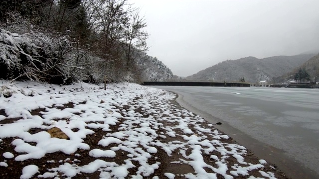 徒步者POV在下雪的时候走在结冰的湖边视频素材