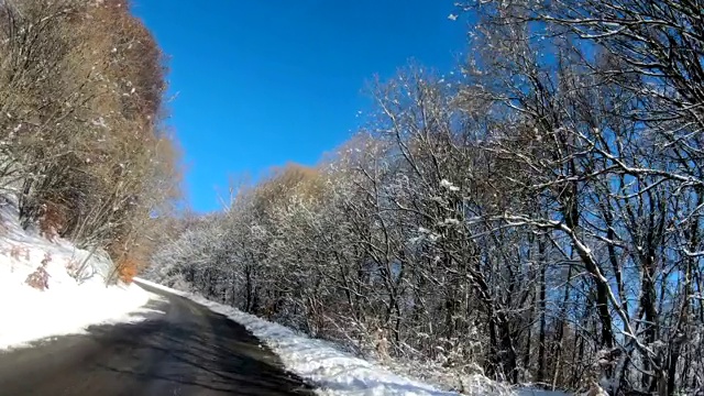 行驶在风景优美的山路上，在冰雪覆盖的荒野森林里视频素材