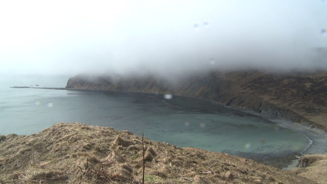 雾笼罩着一个小海湾的岩石山坡。视频素材