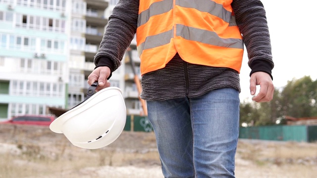 土木工程师正在建筑工地上，手里拿着一顶白色的头盔视频素材