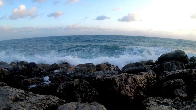 日落时海浪拍打着布满岩石的海滩视频素材