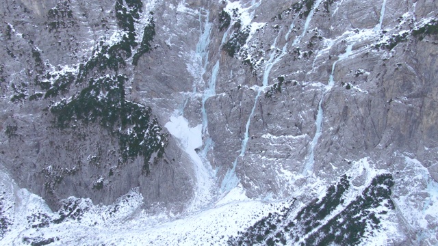 AERIAL:冰冻的河流从斯洛文尼亚一座雪山的悬崖上倾泻而下。视频素材