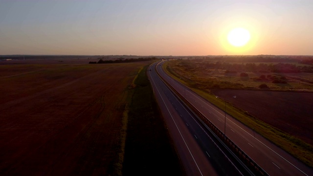 许多汽车是移动的夕阳。空中拍摄的车辆在美丽的乡村道路在日落。鸟瞰道路上的汽车与日落的背景。视频素材