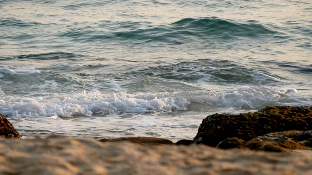 4 k。海浪的泡沫泡沫的海滩上的岩石。热带夏季海滩度假背景镜头，选择性聚焦。视频素材