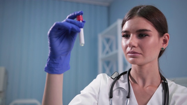 护士医生拿着一根试管，仔细地检查它视频素材