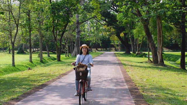 快乐的亚洲女人骑自行车外出，旅游和观光的概念。视频素材