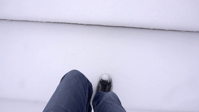 一个男人走在雪地上，把腿从镜头上挪开，背景，冬天，慢镜头视频素材