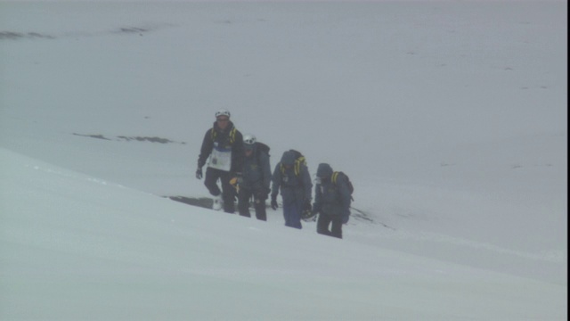 一支徒步旅行队在暴风雪中艰难地爬上一座山。视频素材