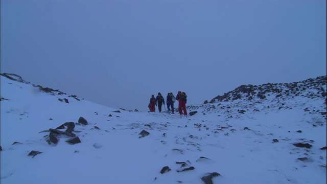 登山运动员徒步穿越山顶的积雪。视频素材