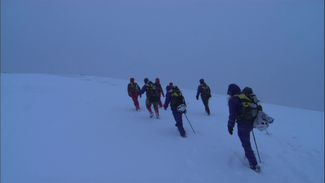 登山运动员徒步穿越山顶的积雪。视频素材