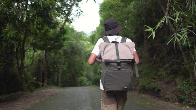 一名男性旅行者背着背包走在乡间小路上视频素材